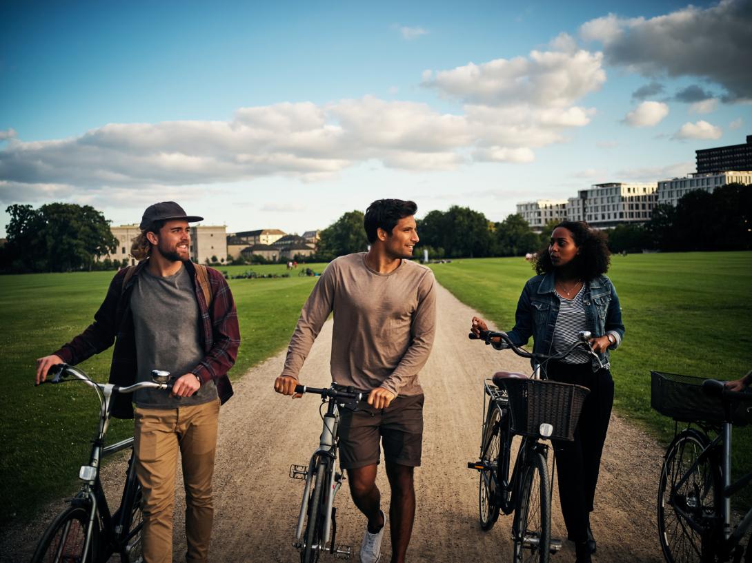 3 Menschen mit Fahrrad im Park